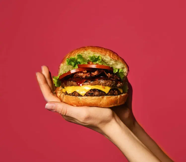 A hand holding a delicious burger