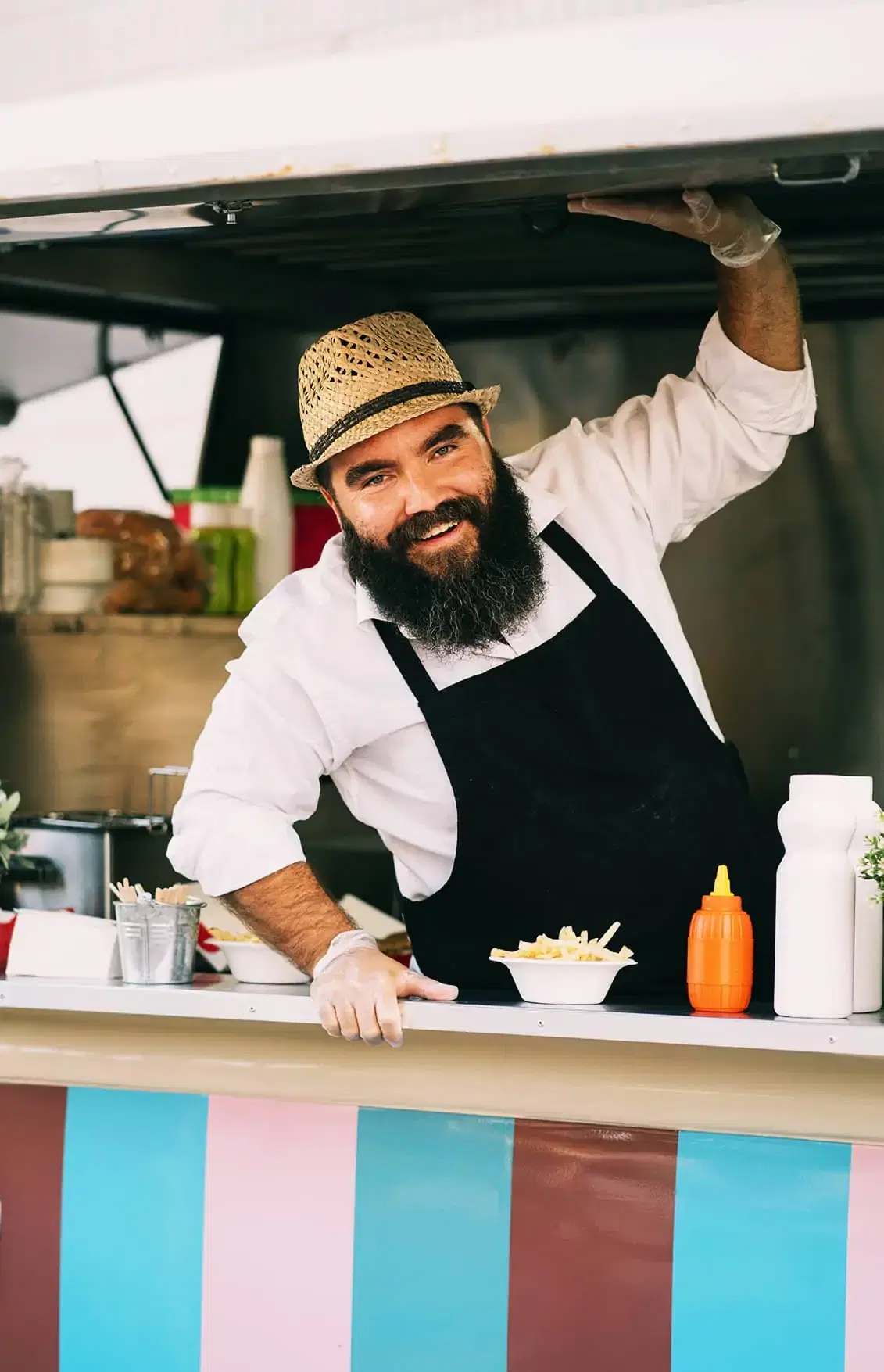 Friendly food truck owner smiling through his service window