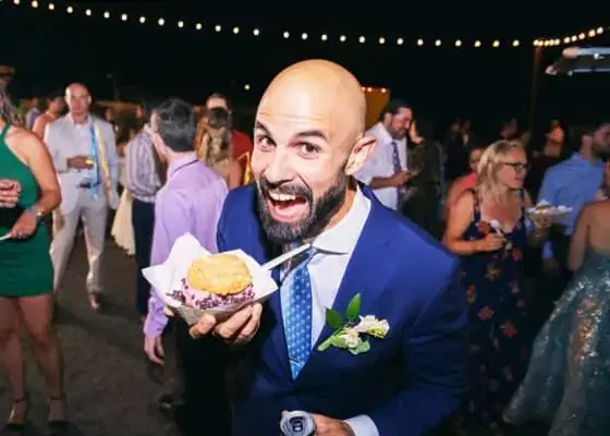Groom at a trendy wedding holding an ice cream sandwich from a food truck